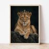 Картина с лъвица с корона в светла дървена рамка, облегната на бяла стена върху паркет Картина с лъвица с корона в светла дървена рамка, облегната на бяла стена върху паркет