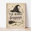 Картина с надпис за вещица в светла дървена рамка, облегната на бяла стена върху паркет Картина с надпис за вещица в светла дървена рамка, облегната на бяла стена върху паркет